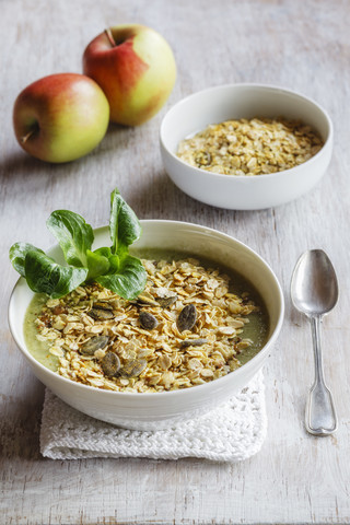 Schale mit grünem Smoothie und einer Mischung aus Haferflocken und Granola, lizenzfreies Stockfoto