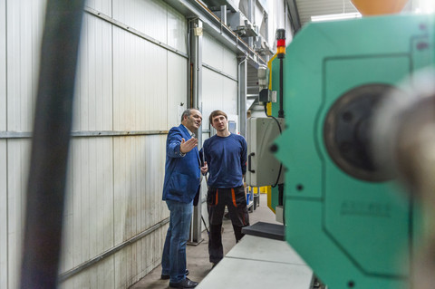 Manager und Arbeiter in einer Kunststofffabrik im Gespräch über Produktionsqualität, lizenzfreies Stockfoto