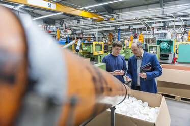 Manager und Arbeiter bei der Prüfung von Kunststoffprodukten in einer Fabrik - DIGF000118
