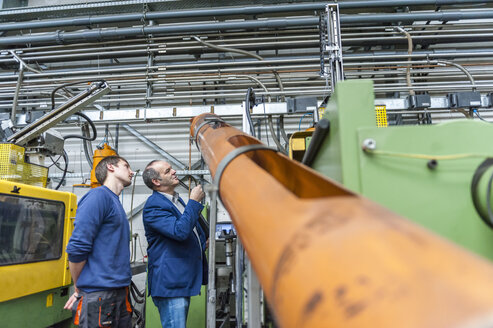 Zwei Personen in einer Kunststofffabrik, die Maschinen untersuchen - DIGF000121