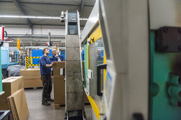 Zwei Personen in einer Kunststofffabrik, die Maschinen untersuchen - DIGF000123