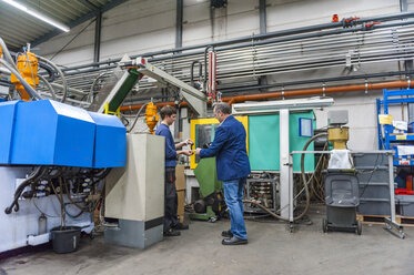 Manager und Arbeiter bei der Prüfung von Produkten in einer Kunststofffabrik - DIGF000124