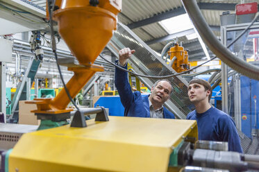 Zwei Personen in einer Kunststofffabrik, die Maschinen untersuchen - DIGF000127