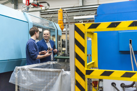 Manager und Arbeiter bei der Prüfung von Produkten in einer Kunststofffabrik, lizenzfreies Stockfoto