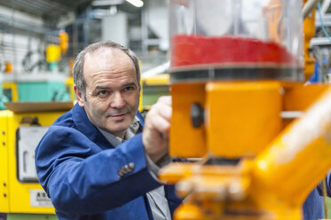Man in plastics factory adjusting production machine - DIGF000139