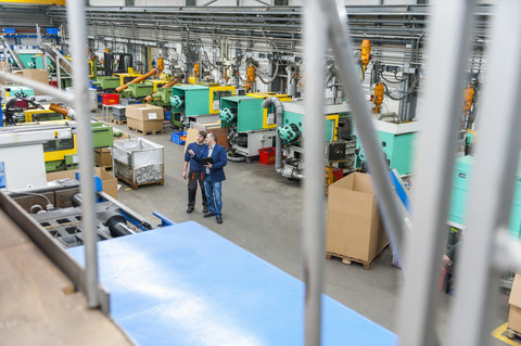 Manager und Arbeiter bei einer Arbeitsbesprechung in einer Kunststofffabrik, lizenzfreies Stockfoto
