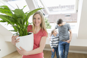 Portrait of smiling woman with potted plant moving in new flat - SHKF000533