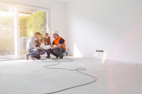 Construction worker explaining family the construction plan stock photo