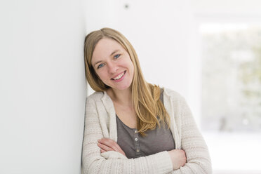 Portrait of happy blond woman leaning against wall - SHKF000566