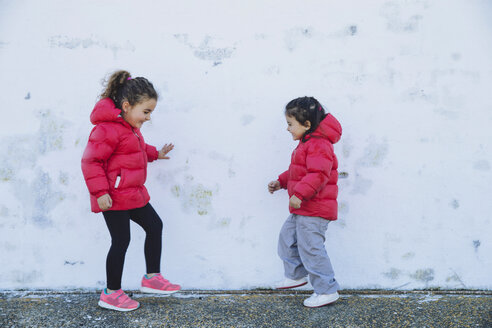 Zwei kleine Mädchen tanzen vor einer Mauer - ERLF000151