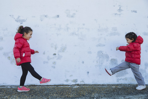 Two little girls playing in front of a wall stock photo