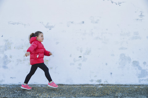 Little girl walking in front of a wall stock photo