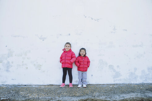 Zwei kleine Mädchen, die vor einer Wand lustige Gesichter machen - ERLF000157