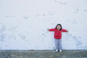Portrait of little girl leaning against with outstretched arms sticking out tongue - ERLF000158