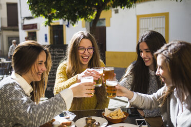 Four happy friends toasting with beer in a street cafe - KIJF000244