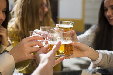 Friends toasting with beer glasses in a street cafe, close-up - KIJF000245