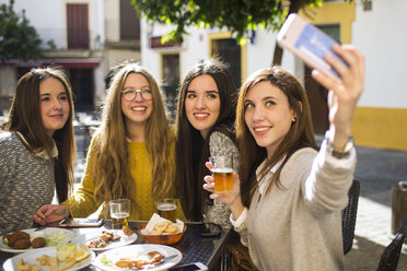 Young woman taking a selfie with her three friends at street cafe - KIJF000246