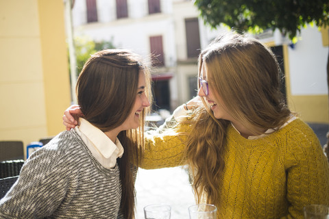 Zwei lachende junge Frauen in einem Straßencafé, lizenzfreies Stockfoto