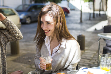 Porträt einer jungen Frau beim Biertrinken in einem Straßencafé - KIJF000248