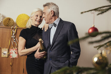 Älteres Paar mit einer Flasche Champagner in der Hand an Silvester - MFF002919