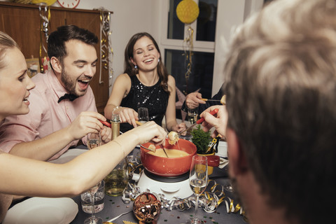 Friends eating cheese fondue on New Year's Eve stock photo