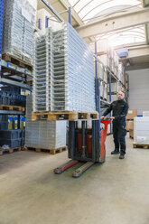 Worker in warehouse transporting goods on forklift - DIGF000166