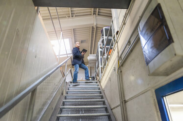 Manager steht auf der Treppe und kontrolliert die Waren im Lager - DIGF000213