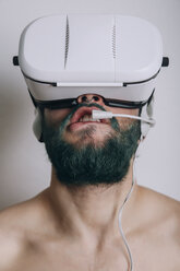 Shirtless man wearing Virtual Reality Glasses and headset biting his lip - RTBF000057