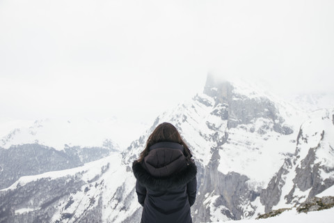 Frau vor einem verschneiten Berg in den Picos de Europa, lizenzfreies Stockfoto