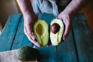 Hands holding two halves of an avocado - KIJF000267