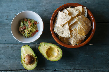 Sliced avocado and bowls of nacho and guacamole - KIJF000280