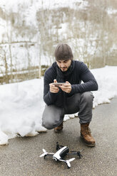 Spanien, Asturien, Mann mit Fernsteuerung und Drohne im Winter - MGOF001626