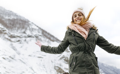 Spanien, Asturien, glückliche junge Frau beim Springen in den schneebedeckten Bergen - MGOF001639