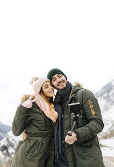 Spanien, Asturien, Paar macht Selfie in den schneebedeckten Bergen - MGOF001642