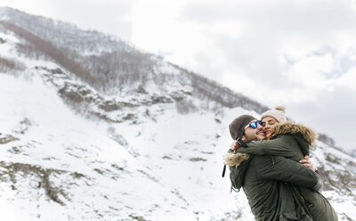 Spanien, Asturien, sich umarmendes Paar in den verschneiten Bergen - MGOF001645