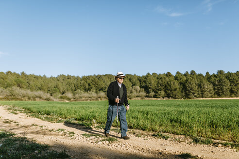 Spanien, Tarragona, Älterer Mann geht mit Stöcken im Feld - JRFF000502