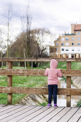 Back view of little girl standing on a footbridge looking at water - MGOF001646