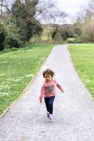 Kleines Mädchen läuft in einem Park, lizenzfreies Stockfoto