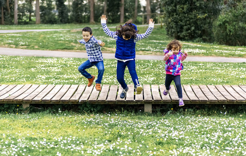 Drei Kinder springen in einem Park, lizenzfreies Stockfoto