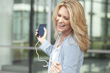 Happy woman listening to music from smartphone - MAEF011408