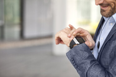 Nahaufnahme eines Geschäftsmannes mit Blick auf eine Smartwatch - MAEF011415