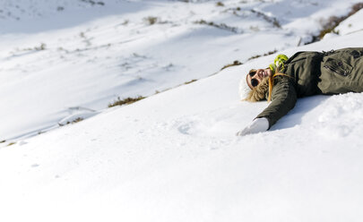 Spanien, Asturien, verspielte Frau im Schnee liegend - MGOF001653