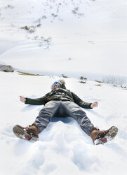 Spain, Asturias, playful man lying in snow - MGOF001654