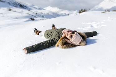 Spain, Asturias, playful woman lying in snow - MGOF001662
