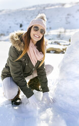 Spanien, Asturien, junge Frau baut einen Schneemann - MGOF001666