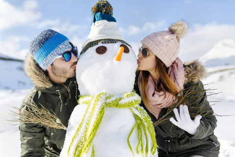 Spanien, Asturien, Paar küsst einen Schneemann, lizenzfreies Stockfoto