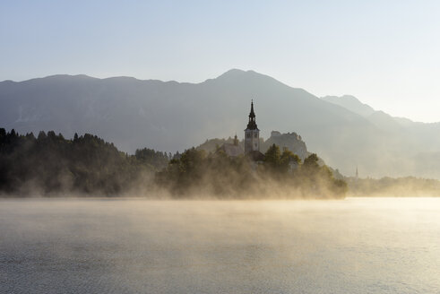 Slowenien, Gorenjska, Bled, Insel Bled, Wallfahrtskirche Mariä Himmelfahrt und Bleder See im Morgennebel - RUEF001673