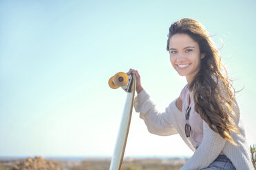 Portrait of smiling teenage girl with longboard - SIPF000292
