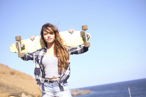 Spanien, Porträt eines Teenagers mit Longboard auf den Schultern - SIPF000295