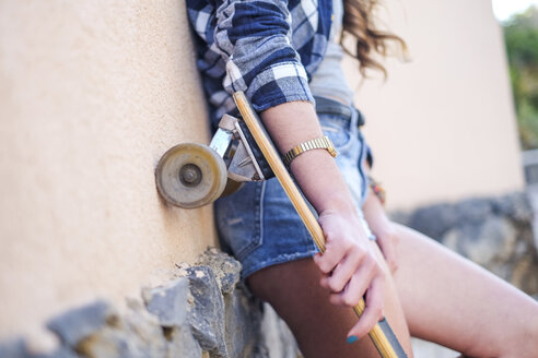 Porträt eines lächelnden Teenagers mit Longboard, der sich gegen eine Wand lehnt, Teilansicht - SIPF000297
